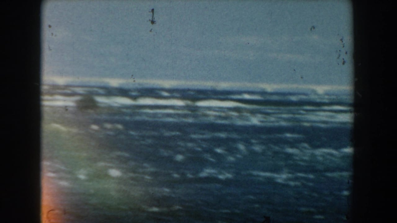 Blue waves under a pale sky with dark 8mm film borders and visible dust.