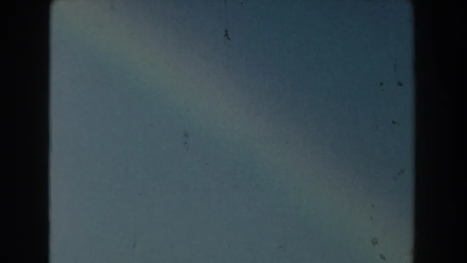 1959 Michigan 8mm frame dominated by pale blue sky, with faint dust, scratches, and a barely visible lower horizon.