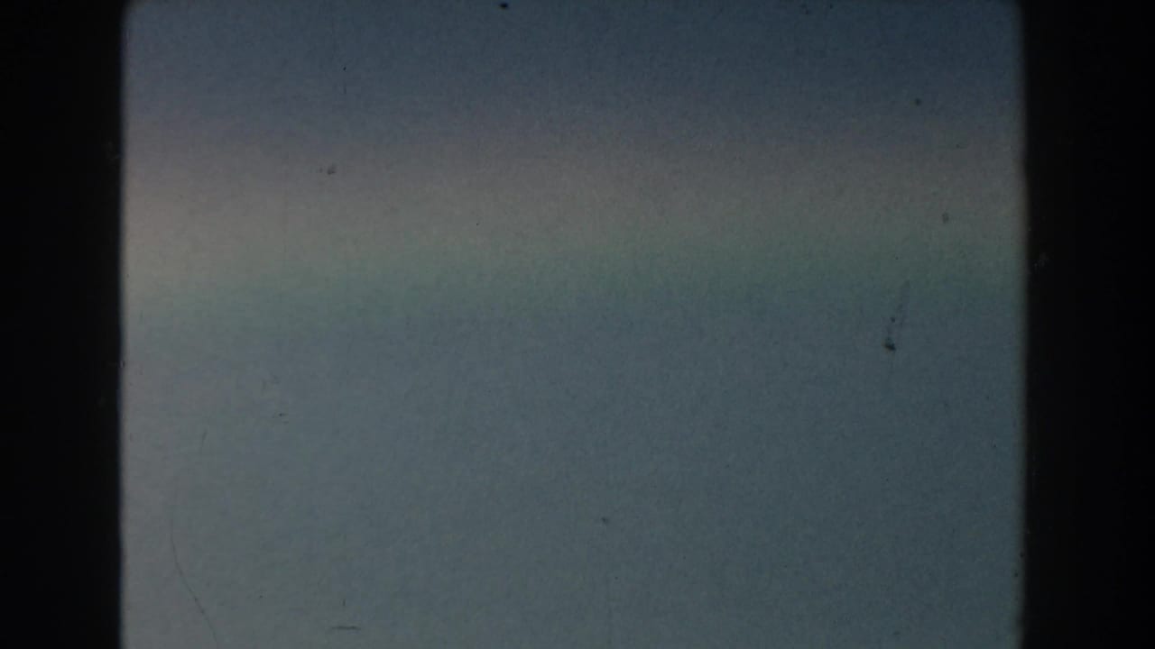 Soft blue-gray sky with thin haze and visible film dust.
