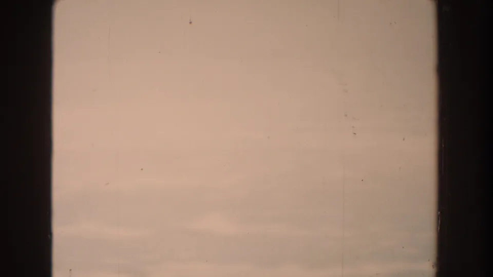 Pale clearing sky with soft pink tones in 1959 Michigan 8mm footage, showing dust, grain, scratches, and dark gate edges.