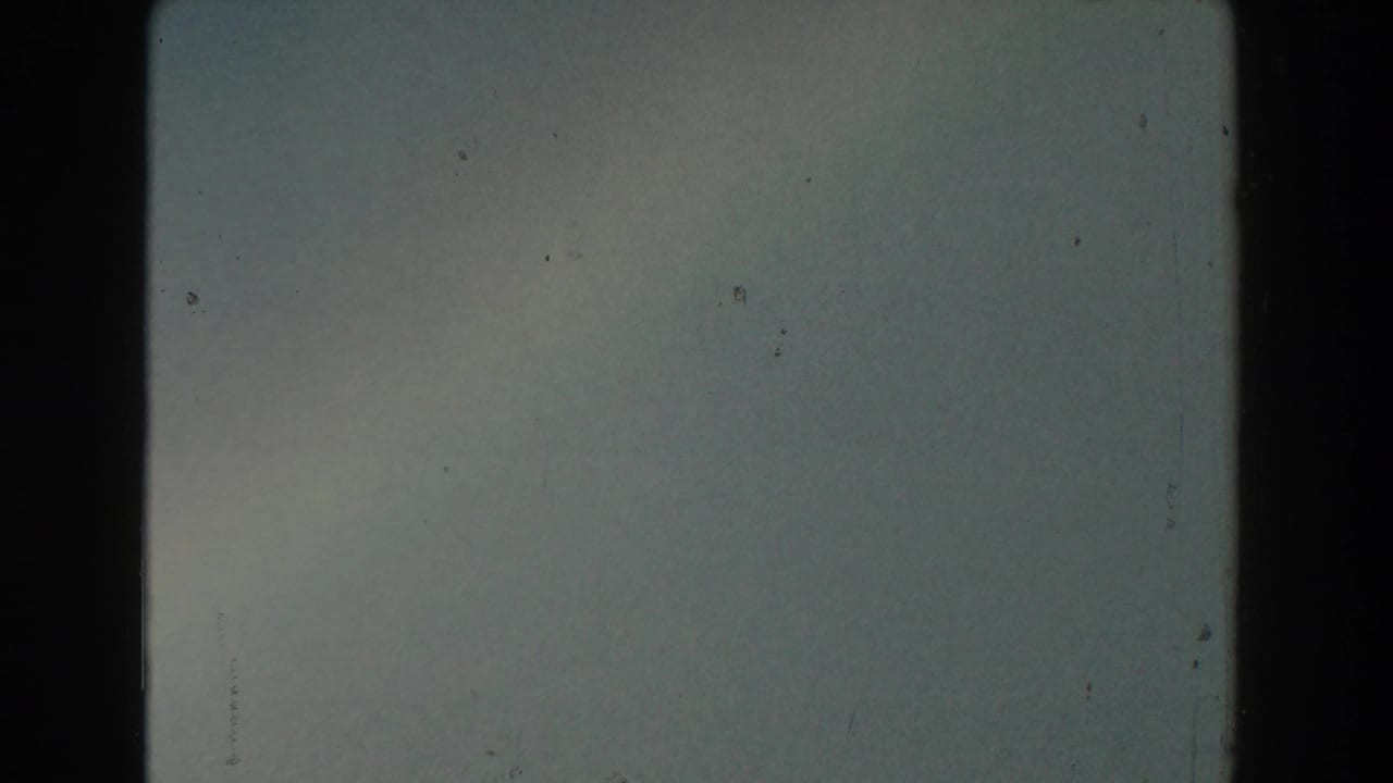 Pale hazy sky with film gate borders and small dust marks.