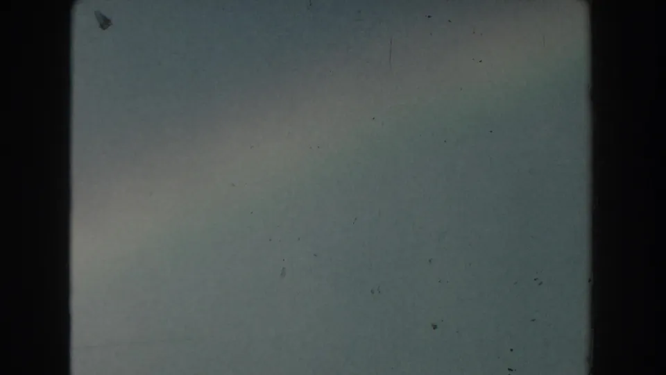 1959 Michigan home-movie frame with a pale sky, faint rainbow color, soft exposure, and visible 8mm dust marks.