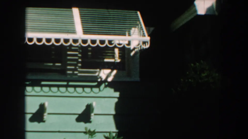 A similar 1959 Michigan exterior view shows a striped awning, window, green siding, and high-contrast sunlight.