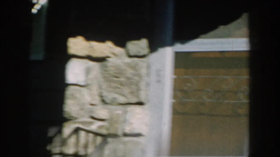 1959 Michigan 8mm frame showing stonework, green siding, white trim, and a shaded doorway or window area.