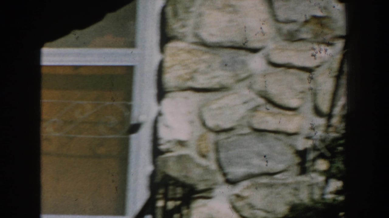 Close view of a stone exterior wall beside a white-framed window.