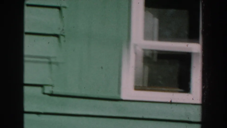 1959 Michigan frame showing green horizontal siding and a white-framed window near the end of the exterior pan.