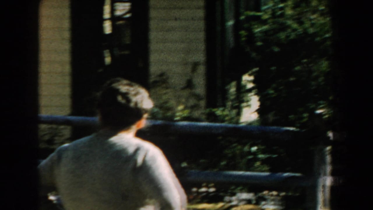 Woman seen from behind near a wooden fence and house exterior.