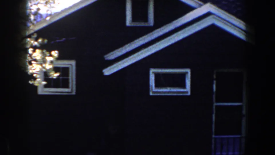 1959 Michigan frame showing the shaded bungalow facade, roof gable, small windows, and tree cover.