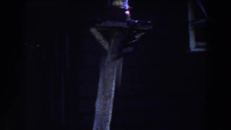 1959 Michigan 8mm frame showing a dim nighttime house exterior with a wooden post, hanging lantern, and small window detail.