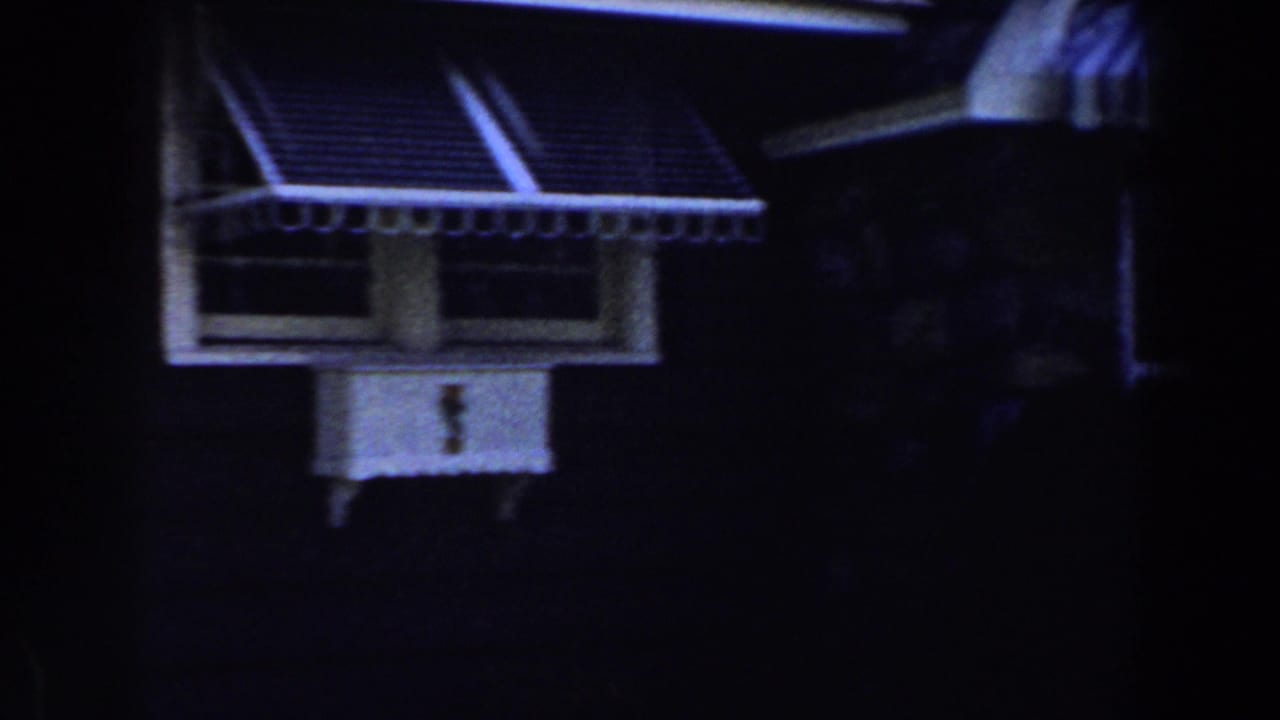 Small window with a striped awning on a dark house exterior.