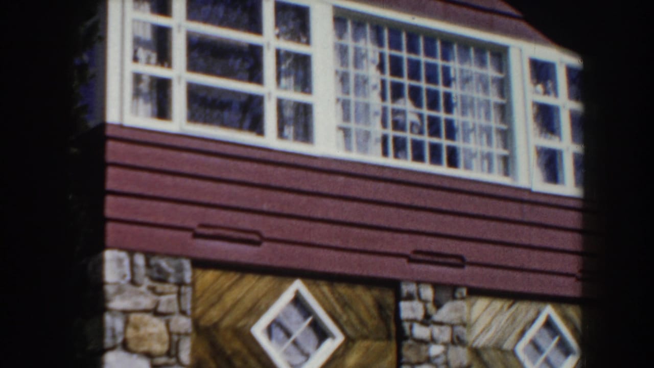 Stone and wood-sided residential building with white windows and diamond basement windows.