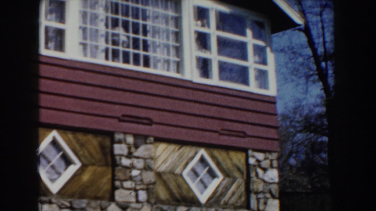 1959 Michigan exterior frame with white multi-pane windows above red-brown siding, stone wall sections, and angled wood panels below.