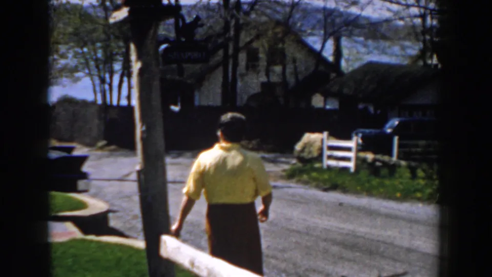 In the final frame, the woman walks away across the suburban yard toward the driveway, with fencing, houses, and trees beyond.