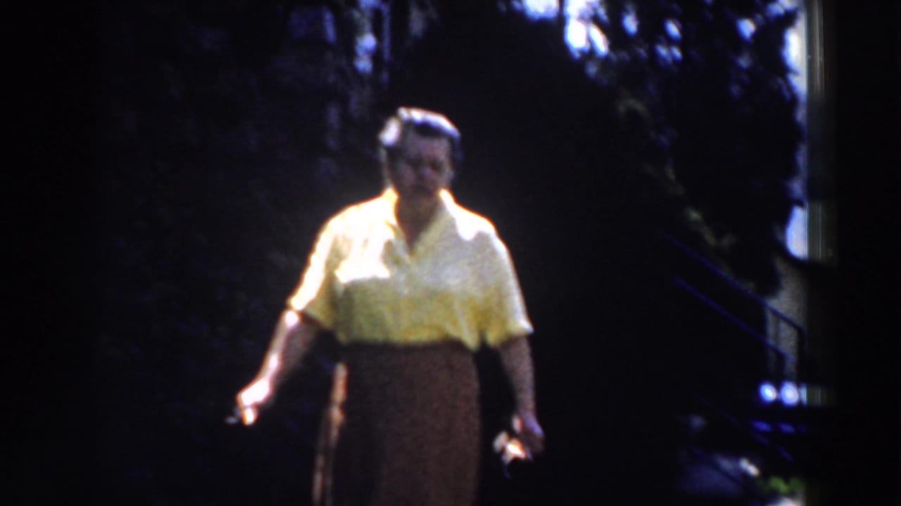 Woman in yellow blouse stands outdoors with one hand lowered.
