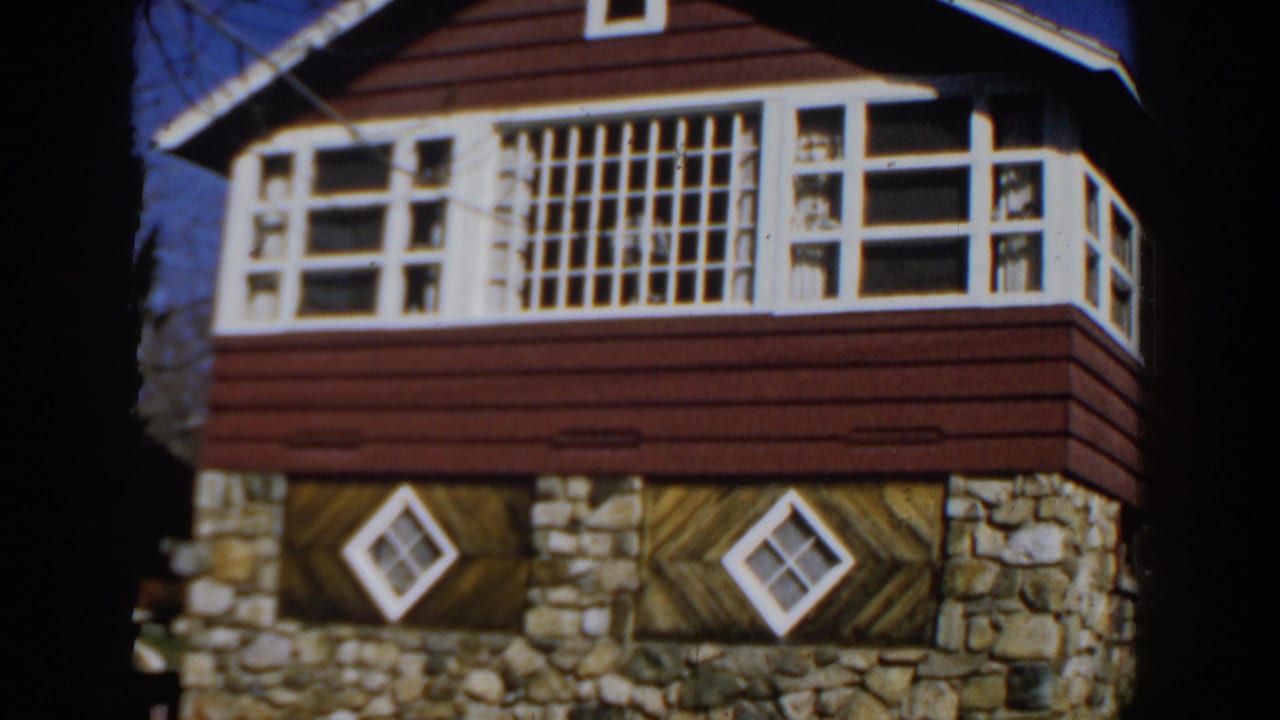 Red wood and stone house exterior with white grid windows and diamond windows.