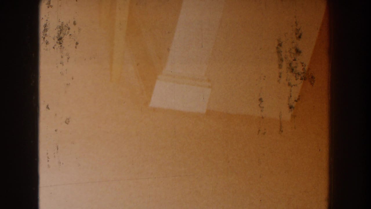 Warm-toned wall and white column base seen through dark 8mm frame edges.