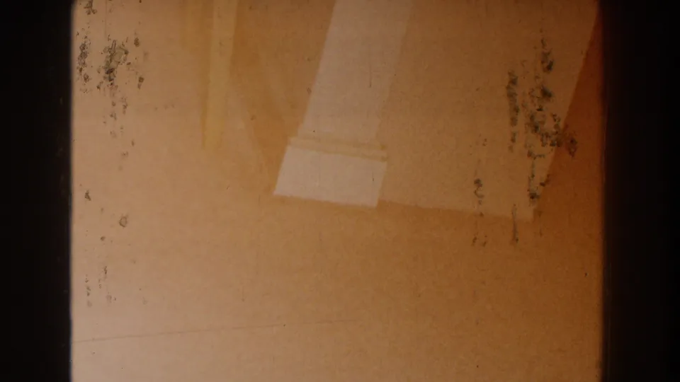 1959 Michigan 8mm frame showing a close interior view of a pale column base against a warm wall with visible film wear.