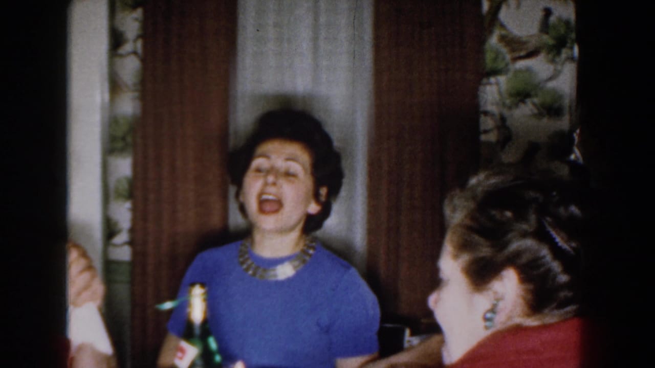 Woman in a blue sweater sings while holding a green bottle near another seated woman.