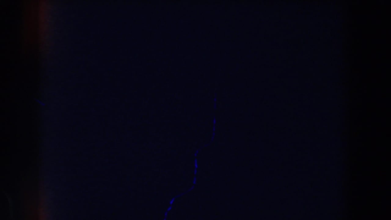 Dark 1959 Michigan 8mm frame with faint blue specks, heavy grain, and little discernible subject matter.