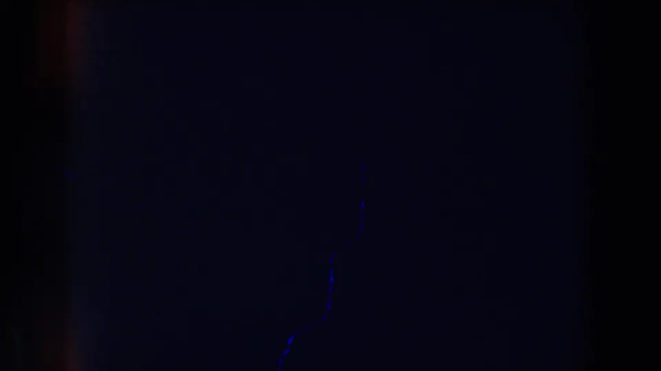 Dark 1959 Michigan 8mm frame with faint blue specks, heavy grain, and little discernible subject matter.