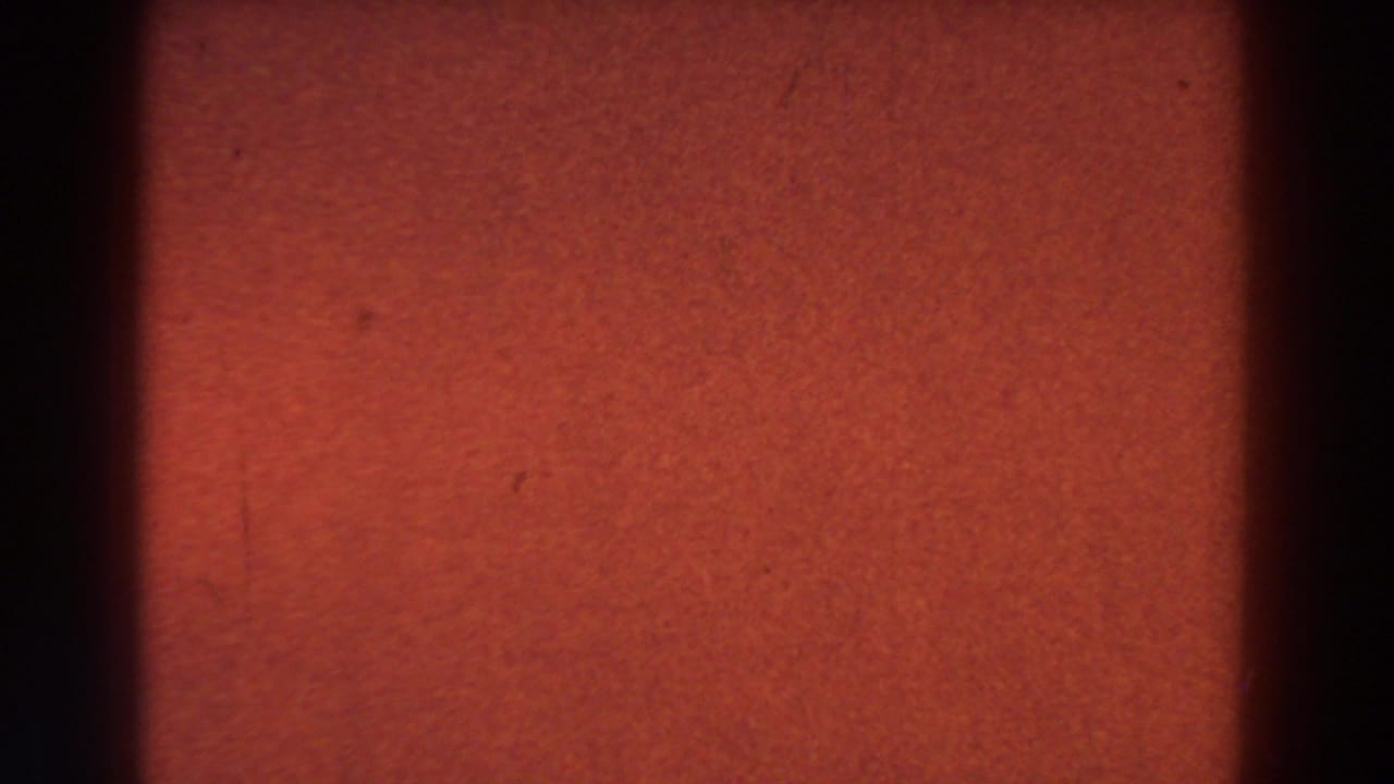 Red-orange exposed film field with a dark vertical band at the left edge.