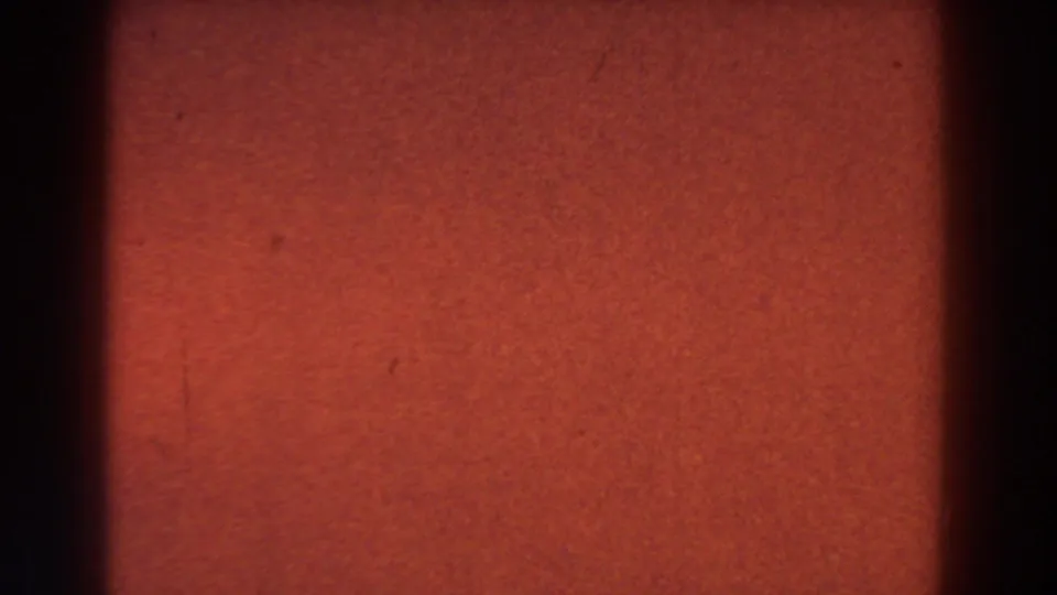 1959 Michigan 8mm frame dominated by red-orange exposure, fine grain, light surface marks, and a dark gate band along the left side.