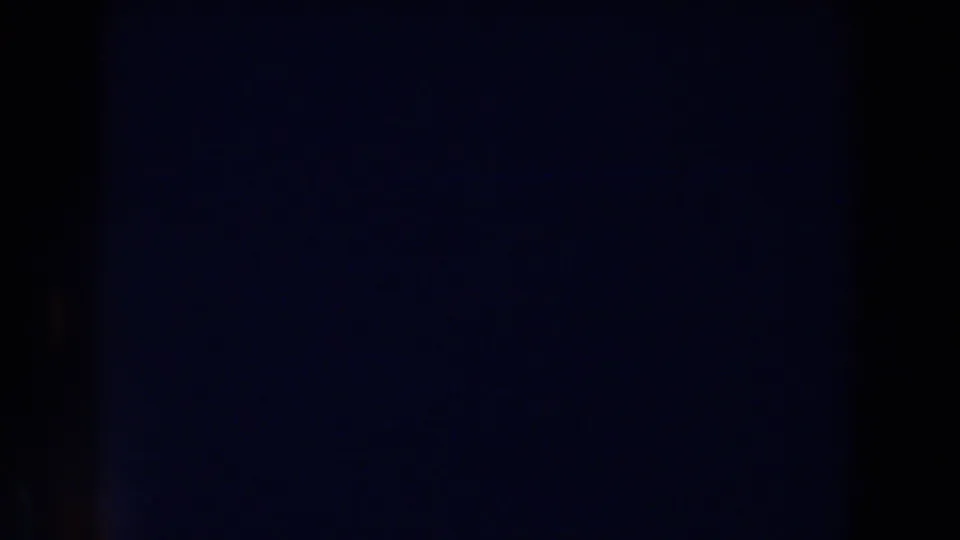 Low-light 1959 Michigan 8mm frame showing a deep blue-black field divided by a soft central dark band.