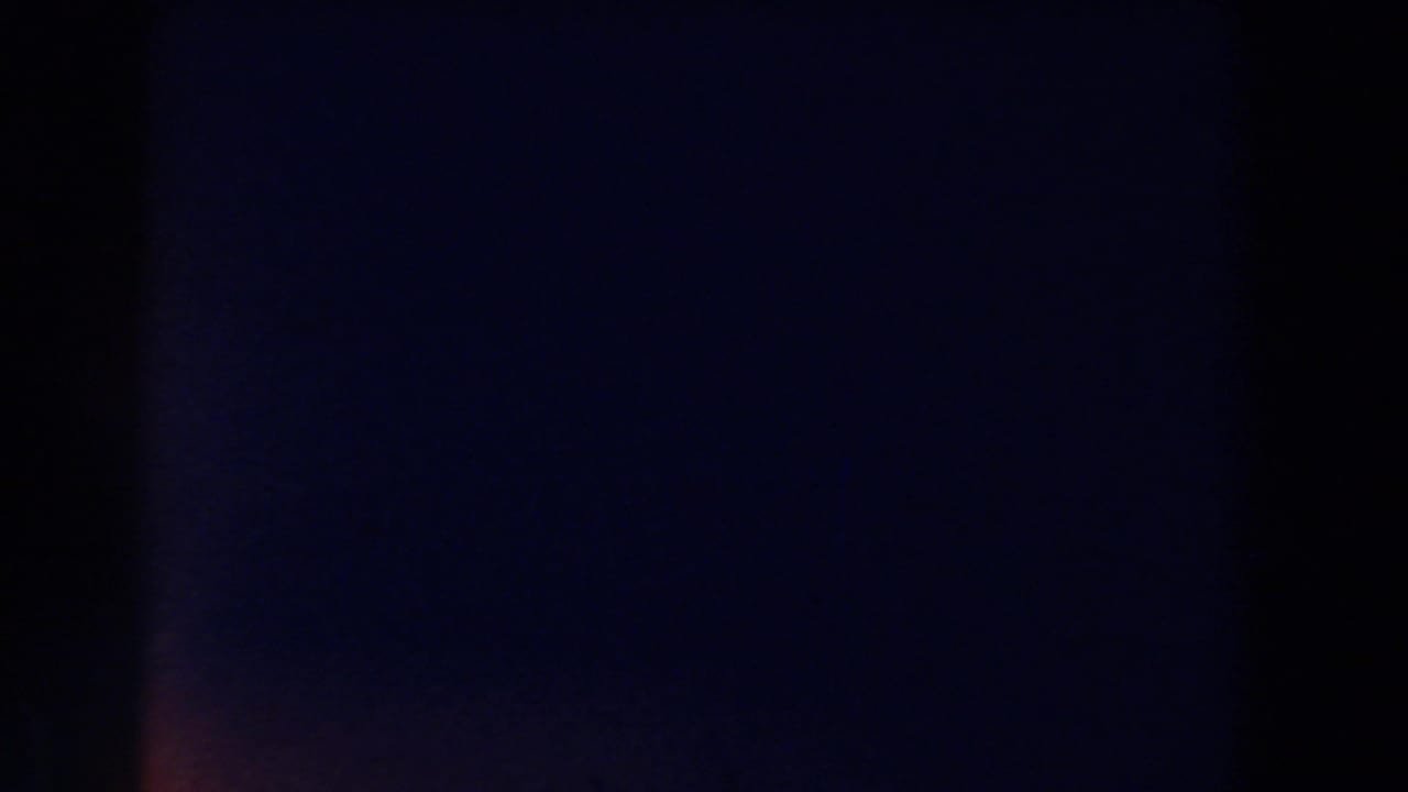 Mostly dark, underexposed film frame with faint purple-blue color shifts.