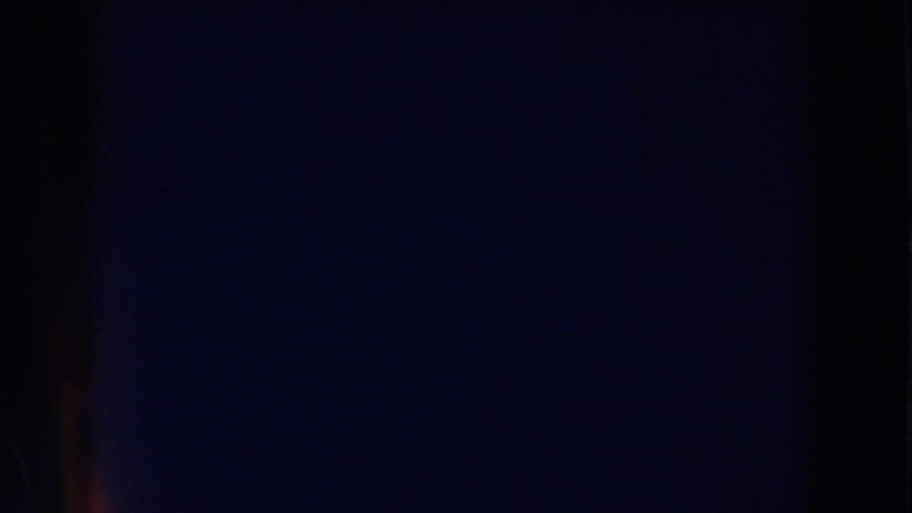 Mostly dark film frame with faint vertical bands and low visible detail.