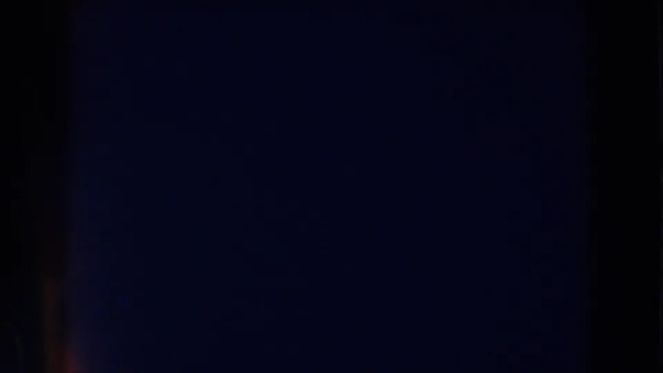 A dim, nearly black 8mm frame shows faint vertical bands and aged color shift before the interior scene becomes visible.