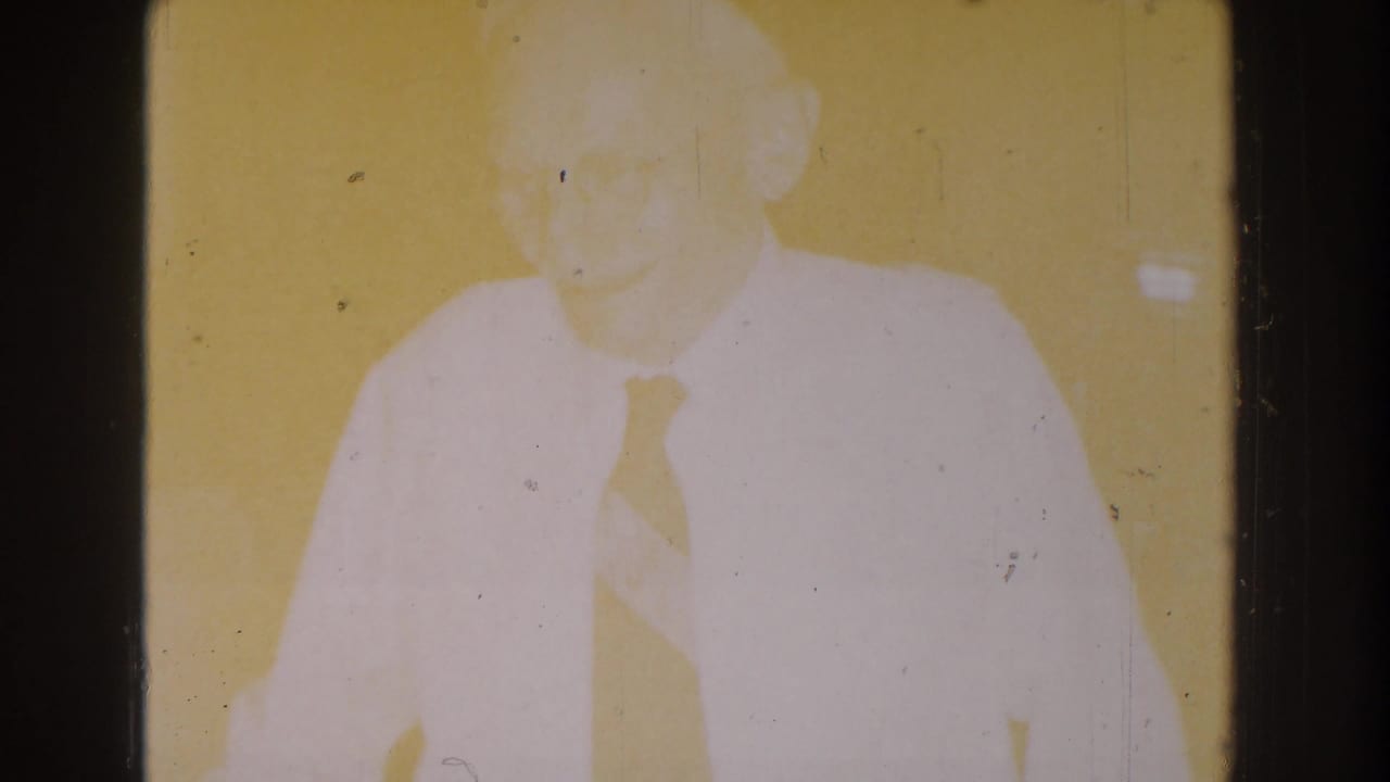 Overexposed frame of the same man in a white shirt and tie.