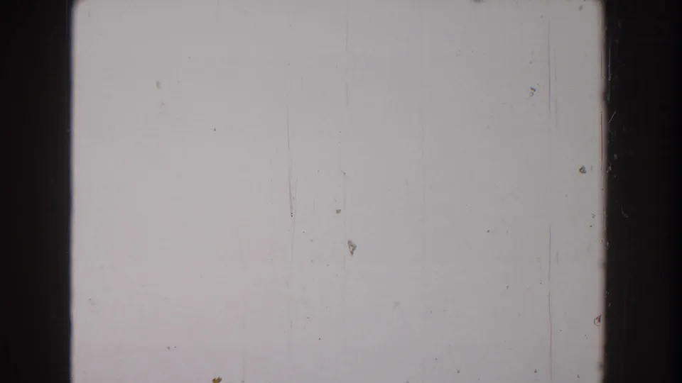 A pale, nearly blank 8mm frame shows dust specks, vertical marks, and faded film texture with no clear subject visible.
