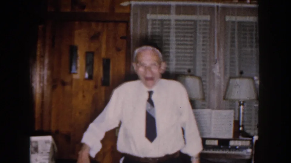 Older Jewish man in a white shirt, dark tie, and yarmulke standing in a Michigan home interior, 1959.