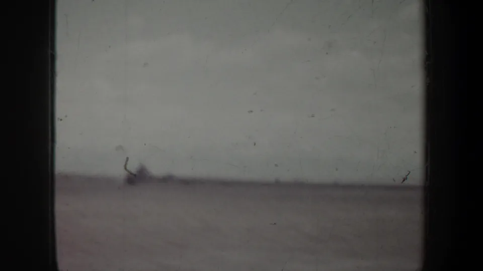 1957 Oregon travel view with a dark car-window divider, low flat land, pale sky, and heavy motion blur from the moving vehicle.