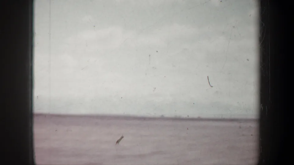 1957 Oregon 8mm frame showing a flat arid horizon under cloud cover, with dark gate edges and visible film wear.