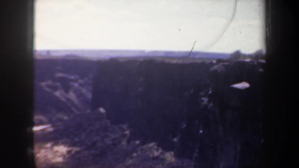 1957 Oregon 8mm canyon panorama with shadowed cliffs, scrubby vegetation, and a winding terrain line below.