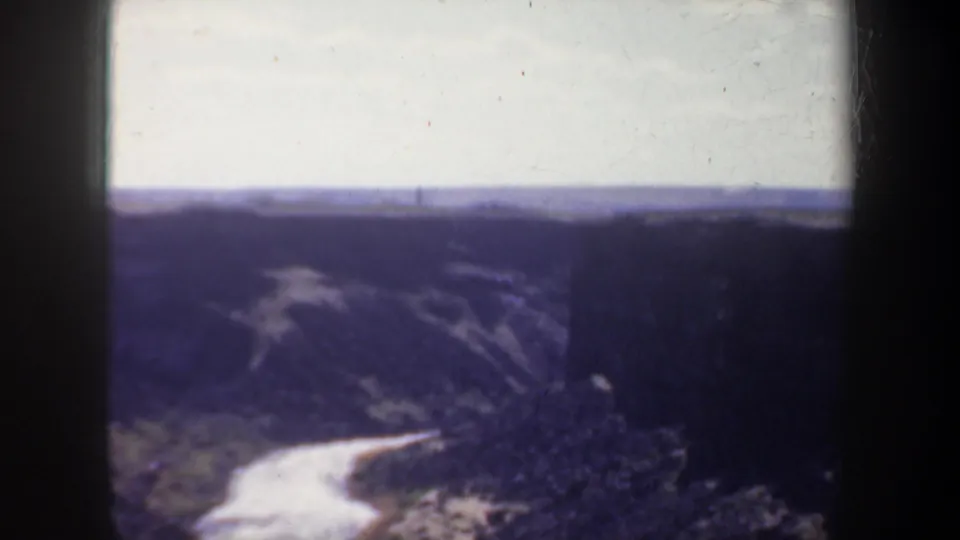 1957 Oregon 8mm frame showing a winding river below dark canyon walls and a distant horizon.