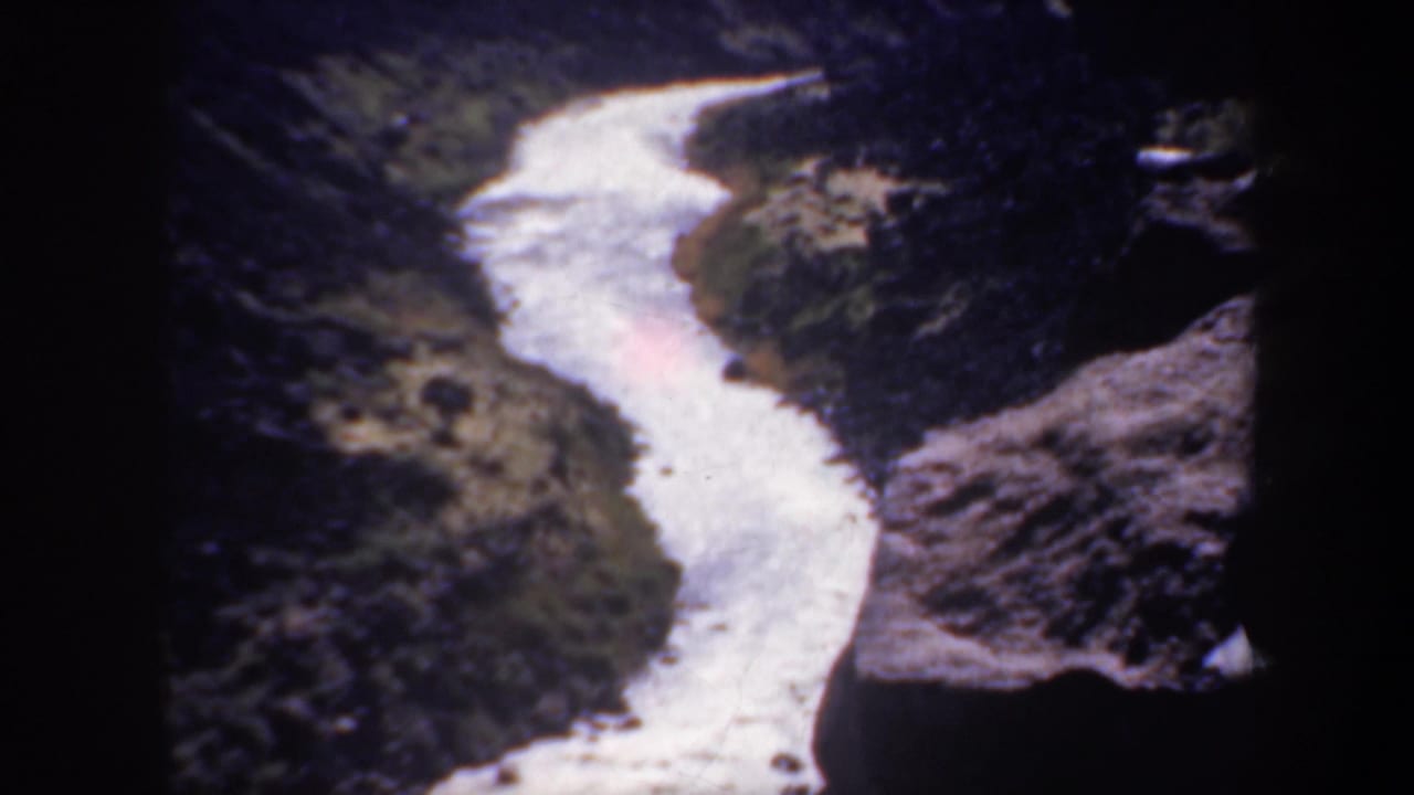 White river channel curves between steep canyon slopes and rocky banks.