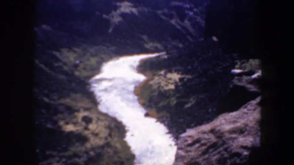 Vintage 1957 Oregon home-movie frame showing a winding river bend below a high viewpoint, bordered by rocky canyon walls and sparse vegetation.