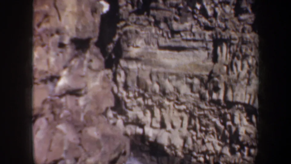 Soft 8mm frame of layered canyon formations in Oregon, with textured rock faces and deep shadowed recesses.