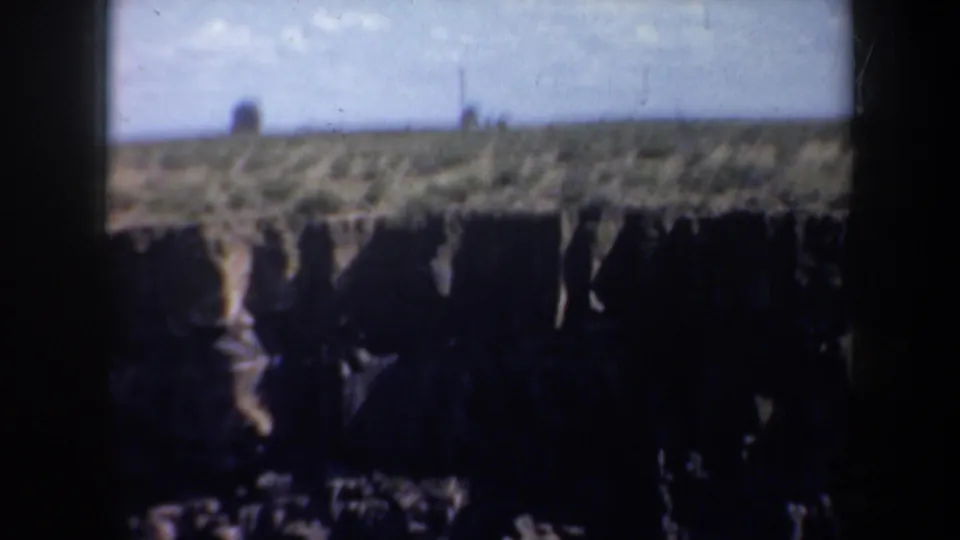 1957 Oregon frame with a distant rocky horizon, pale sky, and dark canyon foreground seen through 8mm film edges.