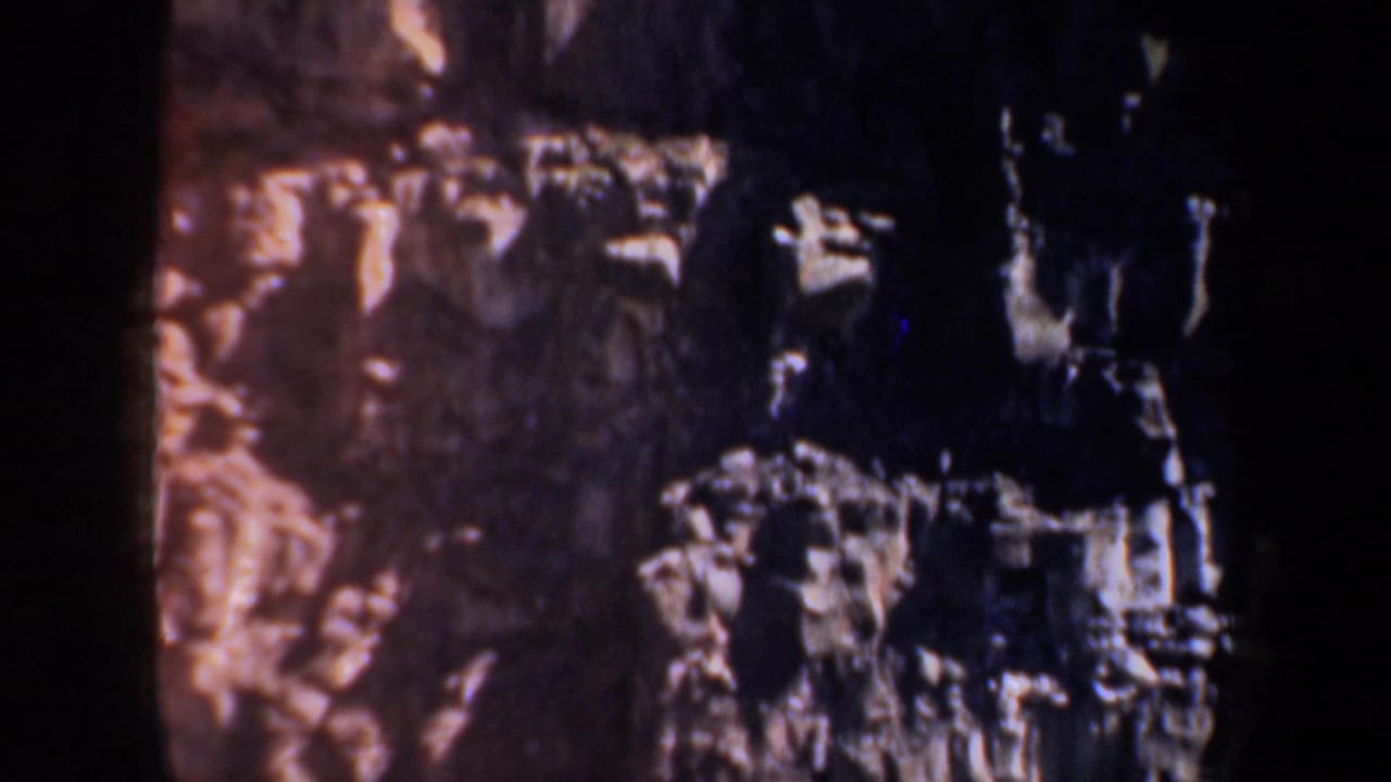 Rock wall with reddish tones and dark vertical shadow areas.