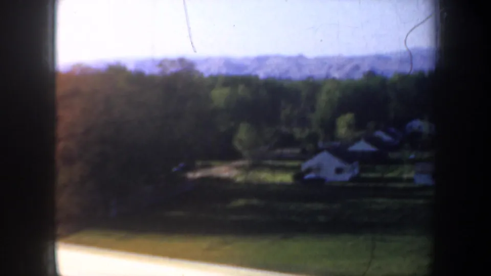 1957 Oregon rural landscape viewed from a moving car, with fields, scattered houses, trees, and distant hills.