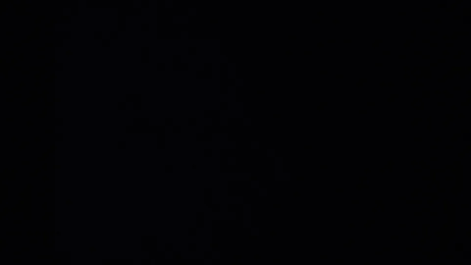 A dark, partially obscured 8mm frame from the Oregon 1957 clip, with only a bright sliver of field visible at right.