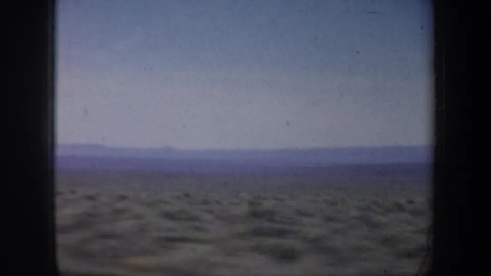 1957 Oregon 8mm landscape with sparse shrubs, a blue-purple horizon, and soft home-movie color.