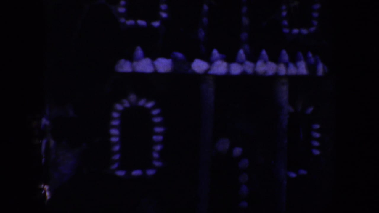 Dark decorative house facade with purple glowing window shapes.
