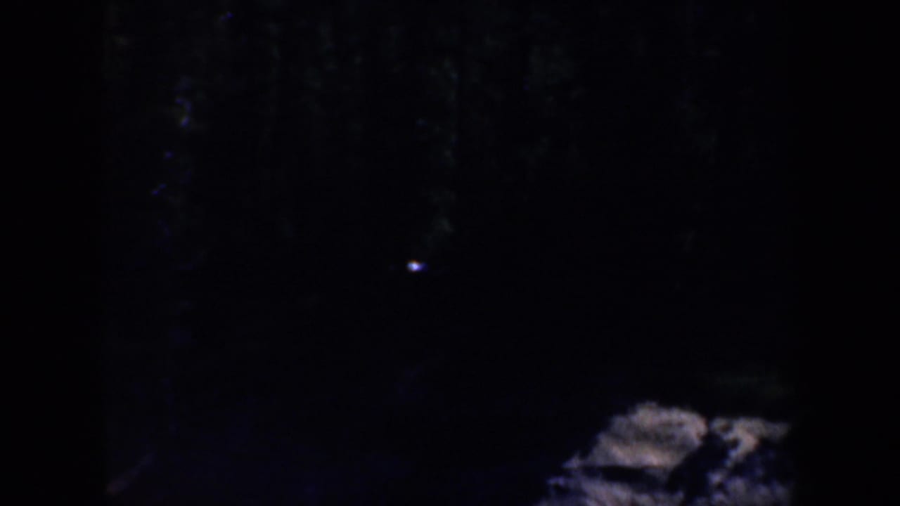 Rock formation in deep shadow with a small bright point nearby.