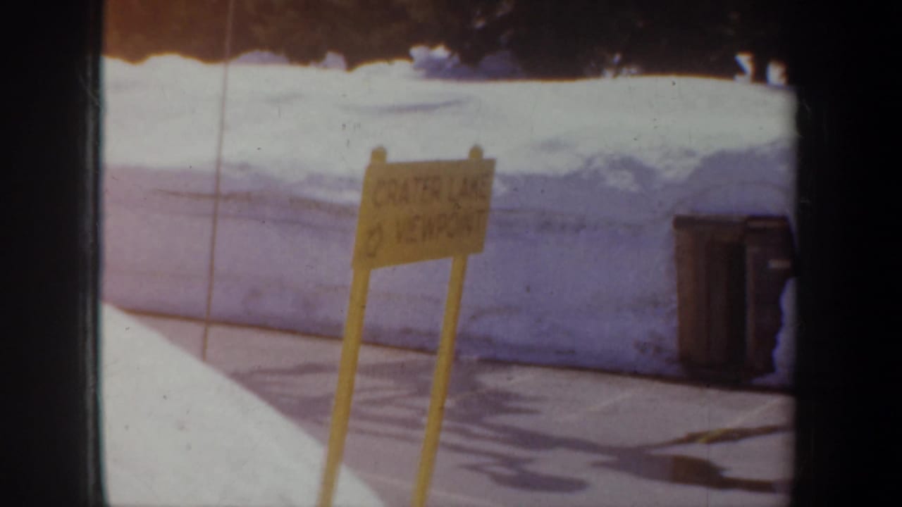 Viewpoint sign in snow with bins and a high snowbank behind it.