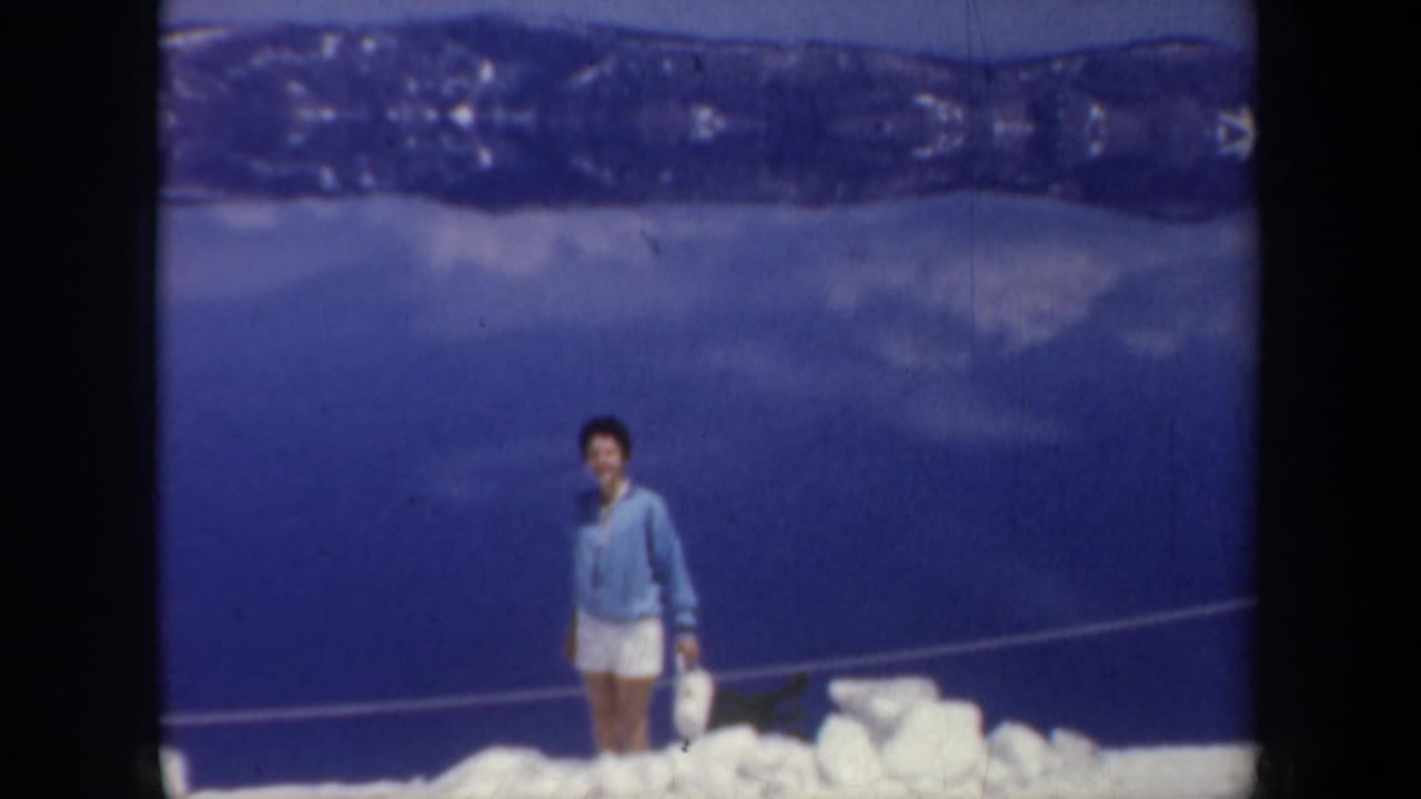 Woman in a blue sweater standing on snow with a dark blue backdrop.