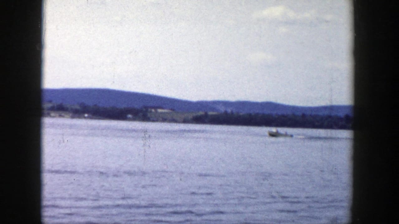 1958 Wisconsin lake view with a small boat far across the water, distant hills, and visible 8mm gate borders.